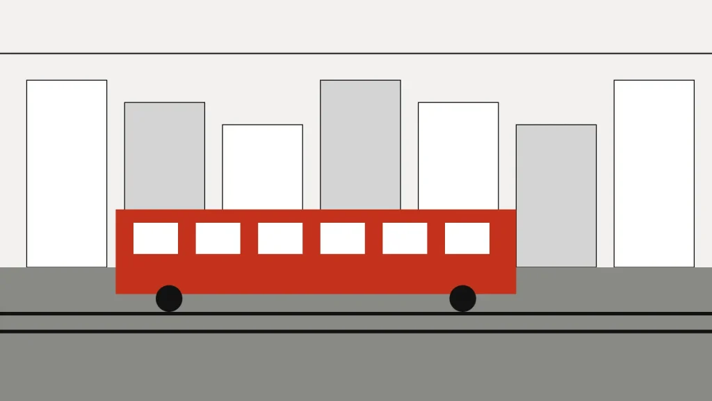 A red tram passes a row of town houses on a street with double tracks