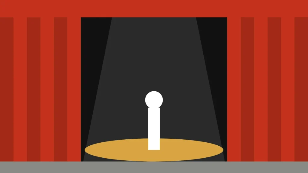 A single figure in a spotlight between red stage curtains
