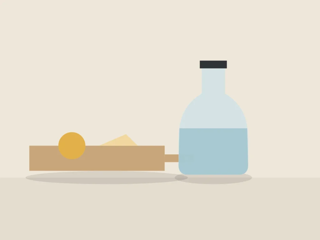 Ash serving board with cheese next to a glass carafe