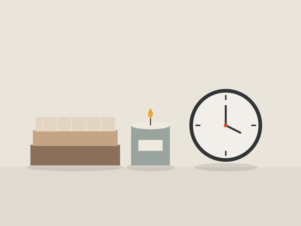 Folded wool throws, a lit candle and a wall clock in warm evening tones