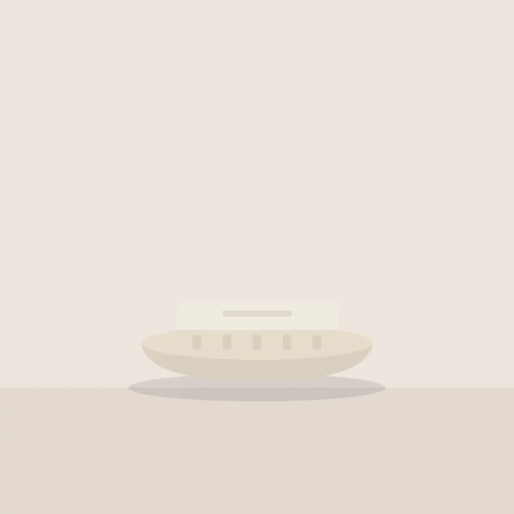Oval stoneware soap dish holding a pale bar of soap